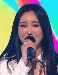 a woman singing into a microphone with a rainbow background