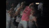a group of people are dancing in a dark room with a tnt logo in the corner