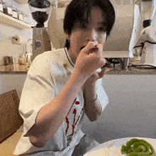 a man wearing a white shirt with the letter v on it is eating something