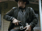 a man in a cowboy hat holds a gun in his hand