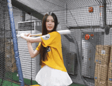 a girl in a yellow shirt is holding a bat