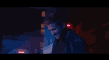 a man is laughing in a dark room with blue and red lights