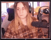 a woman in a plaid shirt is sitting in front of a microphone and headphones .