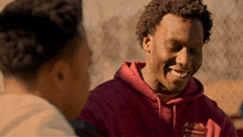 a man wearing a champion sweatshirt is smiling while talking to another man