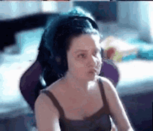 a woman is sitting in a chair wearing headphones and making a funny face .
