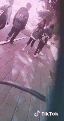 a group of people are walking down a sidewalk on a brick sidewalk .