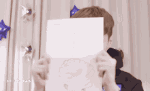 a man holds a piece of paper in front of his face