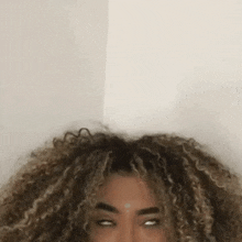 a woman with curly hair is making a funny face while looking at the camera .