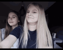 two girls with long blonde hair are posing for a photo