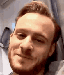 a close up of a man 's face with a beard is smiling .