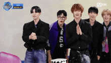 a group of young men standing in front of a sign that says mnet on it