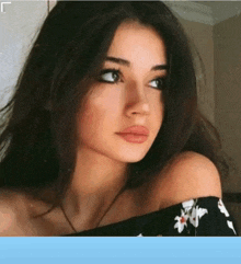 a woman with long dark hair is wearing a black off the shoulder top .