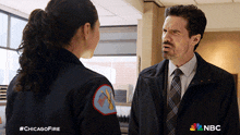 a man and a woman are standing next to each other and the man is wearing a chicago fire jacket