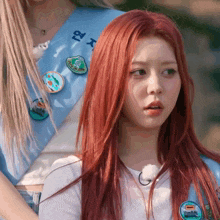 a girl with red hair is wearing a blue sash with korean writing