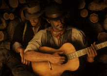 a man playing a guitar next to another man