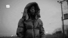 a black and white photo of a man wearing a jacket with a hood .