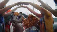 a group of people are holding hands in a circle with a cat costume in the middle