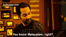 a man in a black shirt is talking to another man in a room .