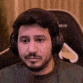 a man with a beard is wearing headphones and making a face .