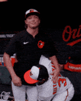 two baseball players are hugging each other in front of a sign that says orioles