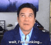 a man in a suit says wait i 'm thinking ...