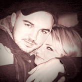 a man in a black hat is hugging a woman in a black shirt