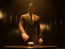 a man in a suit and tie stands in front of a desk