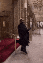 a man in a black coat is standing in a hallway