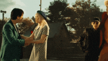 a man in a green suit shakes hands with a woman in a blue hat