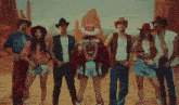 a woman in a pink cowboy hat is dancing in the desert with two men in cowboy hats .