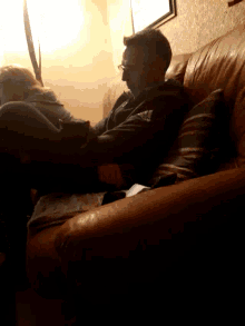 a man sitting on a couch wearing a black adidas shirt