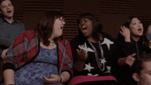a group of people are sitting in a dark room and one of them is wearing a black shirt with white stars on it