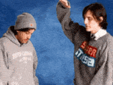 two men wearing sweaters and hats are standing next to each other .