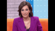 a woman in a purple suit is sitting on an orange chair