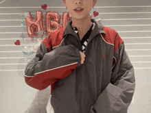 a man in a grey and red jacket is standing in front of a balloon that says hbl