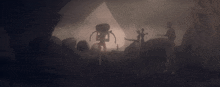 a group of people are standing in a dark cave with a giant alien in the foreground