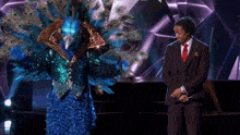 a man in a suit and tie is standing next to a peacock