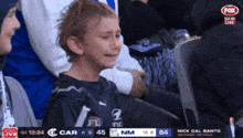 a young boy is crying while watching a game on fox sports