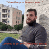 a man with a beard is sitting in front of a building with the words " when the sprint is almost over "