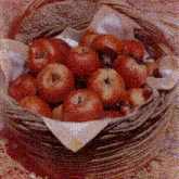a wicker basket filled with red apples is on a table