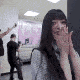a woman covering her face with her hands while a man holds a camera