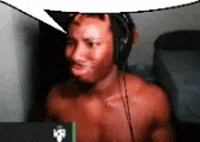 a shirtless man wearing headphones is sitting in front of a laptop computer .