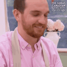 a man in a pink shirt is smiling in front of the great canadian baking show