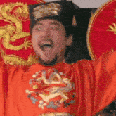 a man in a costume with a dragon on it is holding his arms up in the air .