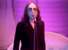 a man with long hair singing into a microphone with his face painted