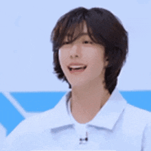 a young man with short hair is wearing a white shirt and waving his hands .