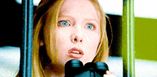 a close up of a woman holding binoculars