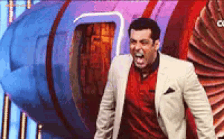 a man in a suit and a red shirt is screaming in front of a blue and red object