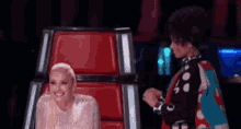 a woman is sitting in a chair next to another woman on a stage .