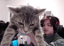 a man wearing headphones is holding a cat in front of him